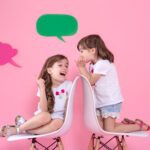 Two Little Girls On Colored Wall With Speech Icons