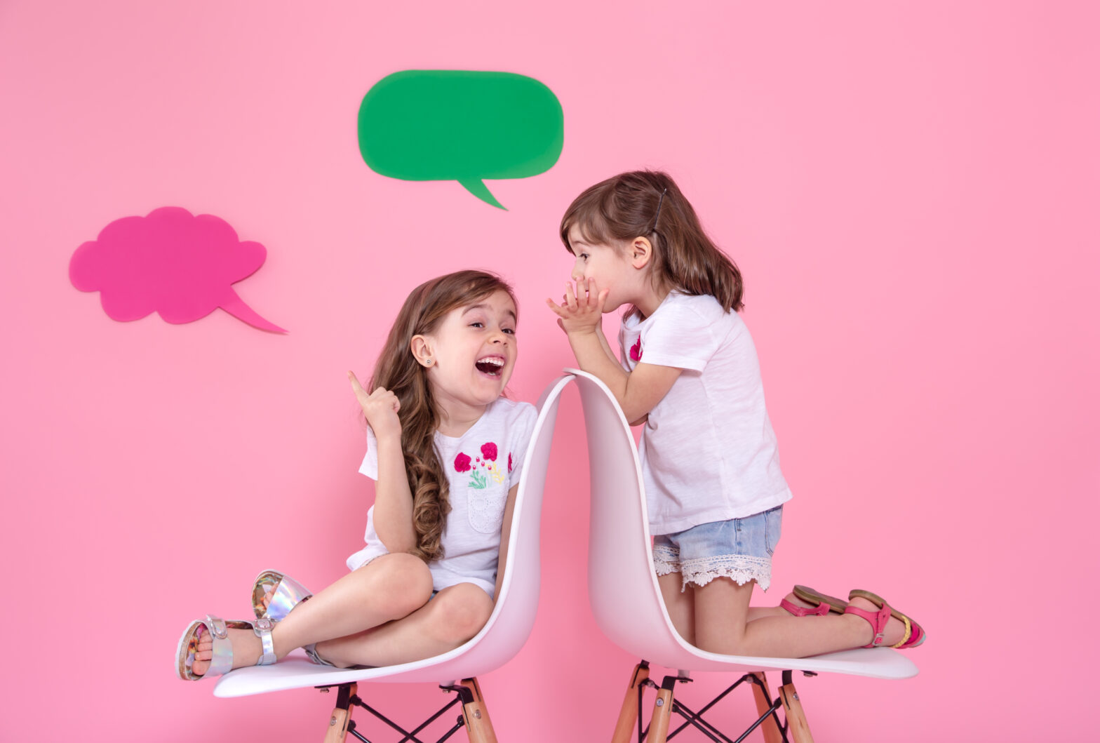 Two Little Girls On Colored Wall With Speech Icons